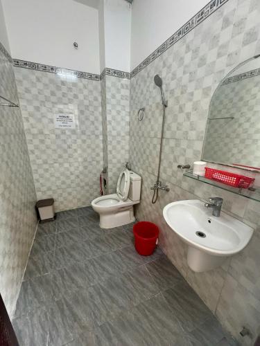 a bathroom with a sink and a toilet and a mirror at Nhà Nghỉ Hoàng Gia Phát in Buôn Kô Sir