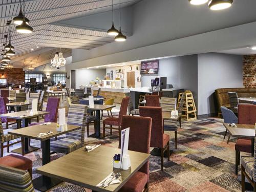 a restaurant with wooden tables and chairs and a cafeteria at Novotel Manchester West in Worsley