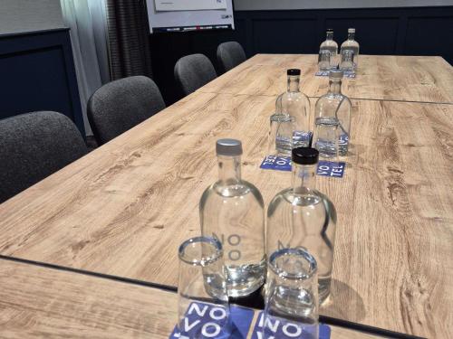 a group of wine bottles and glasses on a wooden table at Novotel Manchester West in Worsley