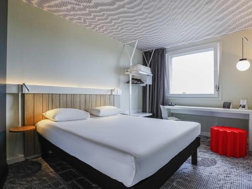 a bedroom with a large white bed and a window at Ibis Luxembourg Airport in Luxembourg