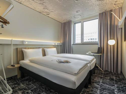a hotel room with a large bed and a window at Ibis Luxembourg Airport in Luxembourg
