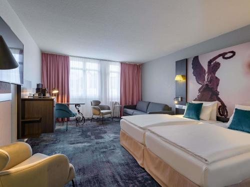 a hotel room with a large bed and a living room at Mercure Hotel Hannover City in Hannover