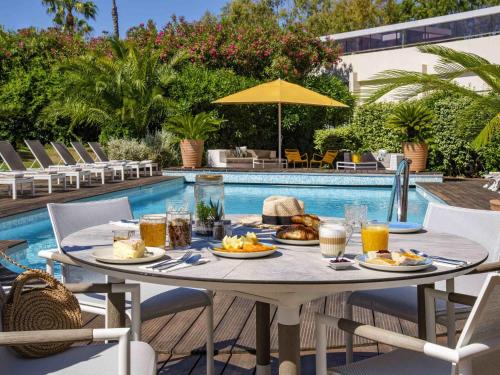 a table with food on it next to a pool at Mercure Hyères Centre Côte d'Azur in Hyères
