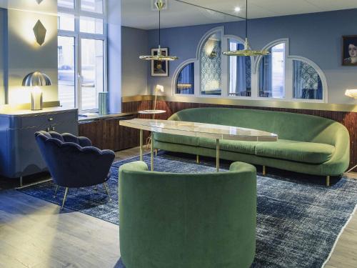 a living room with green furniture and a table and chairs at Mercure Nancy Centre Place Stanislas in Nancy