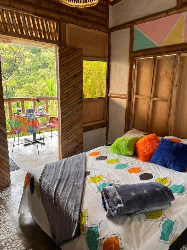 a bedroom with a bed with colorful pillows on it at RIYA Tesoro de la Montaña Cabaña Haly in Ibagué