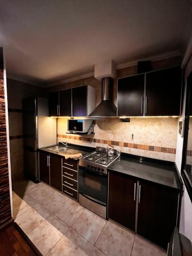 eine Küche mit schwarzen Schränken und einem Herd in der Unterkunft Depto Boutique Chivilcoy in Chivilcoy