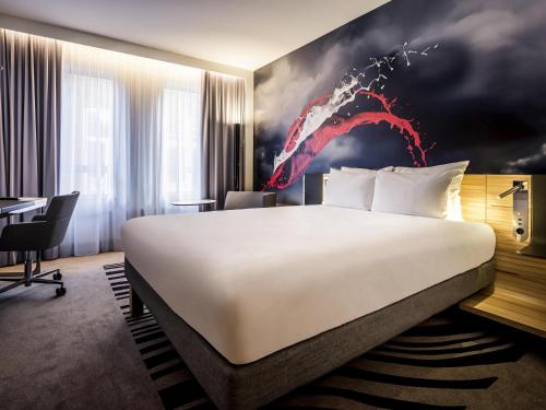 a hotel room with a large bed and a red painting at Novotel Den Haag City Centre in The Hague