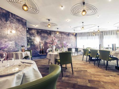 ブール・ガン・ブレスにあるMercure Bourg En Bresseのダイニングルーム(テーブル、椅子付)と壁画