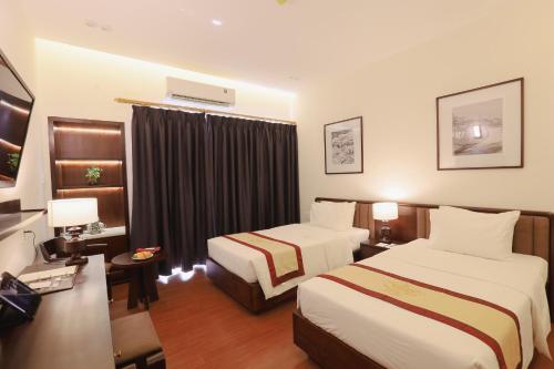 une chambre d'hôtel avec deux lits et une télévision dans l'établissement Huong Giang Hotel Resort & Spa, à Hue