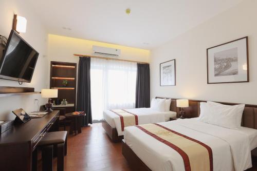 une chambre d'hôtel avec deux lits et un bureau dans l'établissement Huong Giang Hotel Resort & Spa, à Hue
