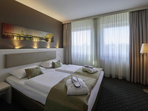 a hotel room with a large bed with towels on it at Mercure Hotel Severinshof Köln City in Cologne