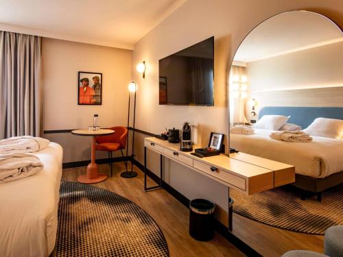 a hotel room with two beds and a desk at Mercure Angoulême Hôtel de France in Angoulême