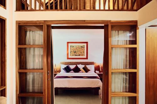 1 dormitorio con 1 cama extragrande y puertas de cristal en Villa Damar Boutique Hotel, en Bandung