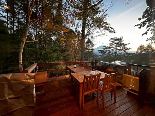 a wooden deck with a table and chairs on it at 富士山を見ながらサウナBBQ The No10 MtFuji Forest House in Yamanakako