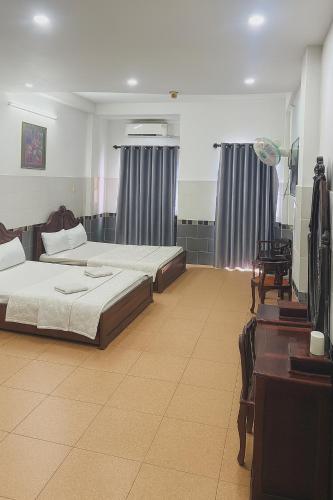 a bedroom with two beds and a dresser and a desk at Tân Ty Mon Hotel in Ho Chi Minh City