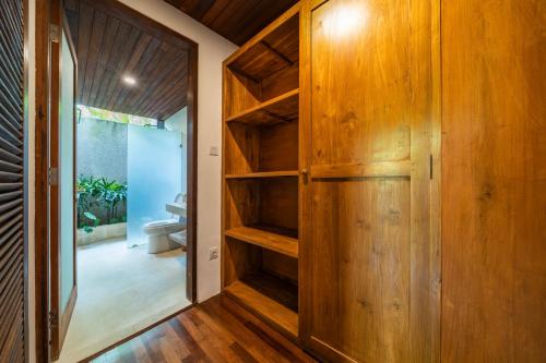 a hallway with wooden cabinets and a toilet in a room at Dua villas Bali - Modern Balinese Escape in Canggu