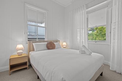 a white bedroom with a large bed with a teddy bear on it at The Coterie Fortitude Valley in Brisbane