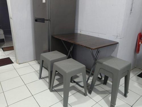 a table and two stools and a table and a refrigerator at AQ Homestay in Labuan