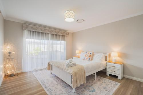 Un dormitorio con una cama blanca y una ventana. en Central Family Home Near Town, en Geographe