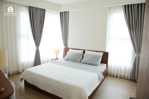 1 dormitorio con 1 cama blanca grande y ventanas en The Glory Midori Park VSIP, en Ga Phú Trung