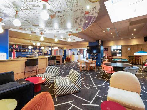 Un restaurante con sillas y mesas y un bar. en ibis Lyon Part Dieu Les Halles, en Lyon