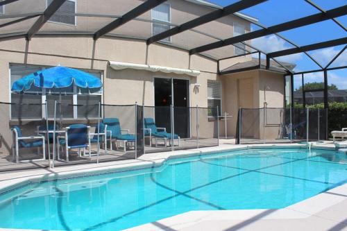 a swimming pool with chairs and an umbrella at Berkeley Pool Home home in Kissimmee