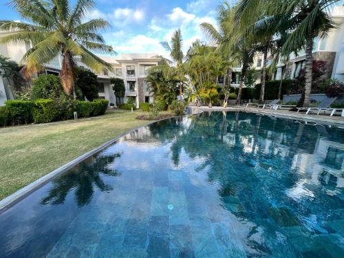 Rivière du RempartにあるAzuri Mauritius Penthouse with Sea Viewsのヤシの木が茂る家の前のスイミングプール