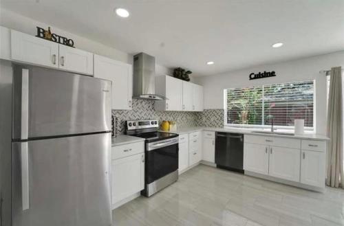 une cuisine avec des armoires blanches et un réfrigérateur en acier inoxydable dans l'établissement Spacious 3BR Oasis Pool Fire Pit & Family Fun, à Cowley