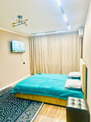 a bedroom with a large bed with a blue blanket at City Apartments in Uralsk
