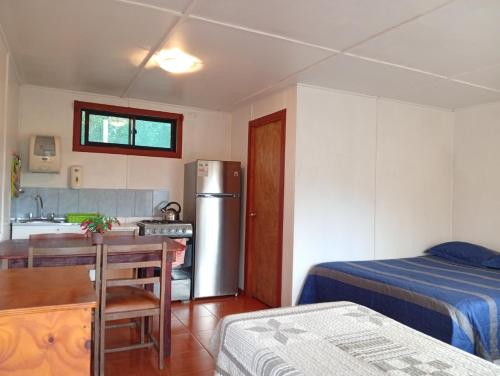 a kitchen with a table and a refrigerator in a room at Cabañas Kravainn in Hanga Roa