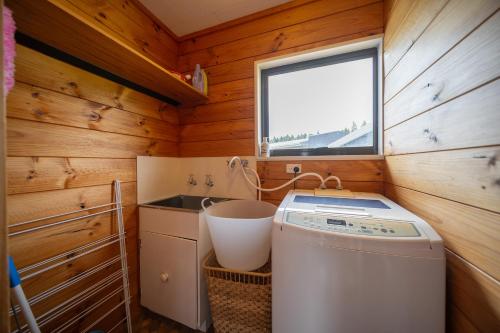 a small bathroom with a washer and a window at The Back Hut - Te Anau Holiday Home in Te Anau