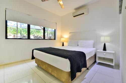 a white bedroom with a bed and a window at Pinnacle Apartments in Hamilton Island