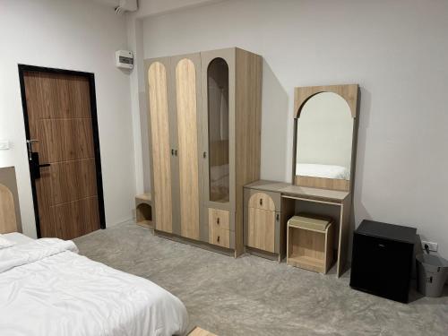 a bedroom with a bed and a vanity and a mirror at GlassHouse in Udon Thani