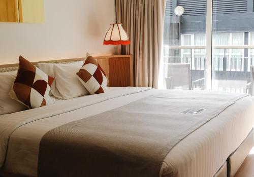 une chambre avec un grand lit avec une grande fenêtre dans l'établissement The Lantern Resorts Patong - SHA Extra Plus, à Patong Beach