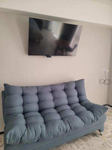 a couch in a living room with a tv on the wall at Suites & Lofts Olivier in Uruapan del Progreso
