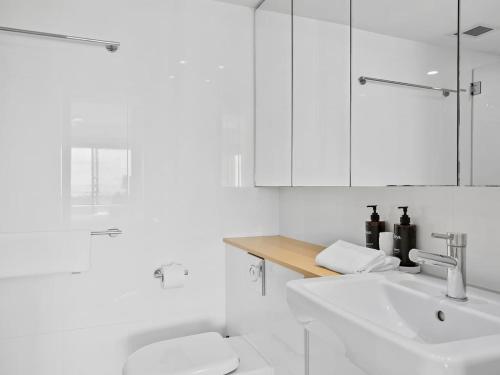 Un baño blanco con lavabo e inodoro. en Noosa Crest Penthouse 34 - Private Rooftop Pool, en Noosa Heads