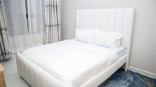 a white bed with white pillows in a room at Parklands Modern 1-Bedroom Apartment near Aga Khan & Diamond Plaza in Nairobi