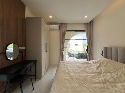a bedroom with a bed and a desk and a window at The Lush Valley Khao yai in Ban Bung Toei