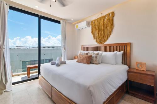 ein Schlafzimmer mit einem großen Bett und einem großen Fenster in der Unterkunft Paravian by Casago in Playa del Carmen