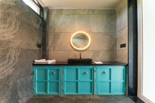 a bathroom with a blue cabinet and a round mirror at Hidden Gem near Jaipur horse ride, scenic view & swimming pool in Pachār
