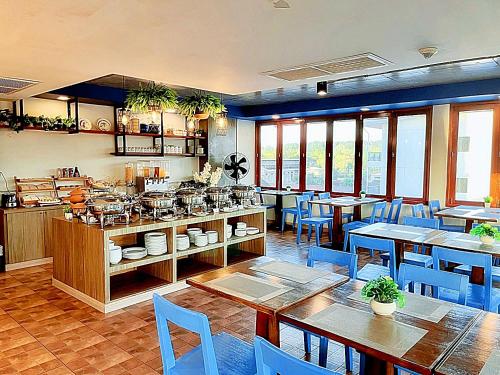a restaurant with tables and blue chairs and a kitchen at The Sixteenth Naiyang Beach Hotel- Free Schedule Airport Shuttle in Nai Yang Beach