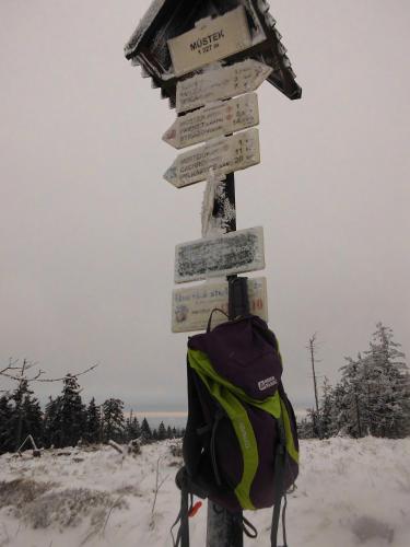 a backpack and signs on a pole in the snow at Turistická ubytovna Zámeček in Hojsova Stráž