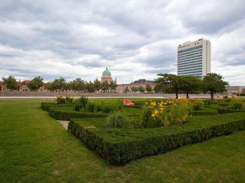 a garden with bushes and flowers in a park at Mercure Hotel Potsdam City in Potsdam