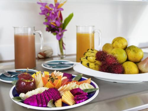 dos platos de comida en una mesa con fruta y zumo en Hotel Mercure Kourou Ariatel, en Kourou