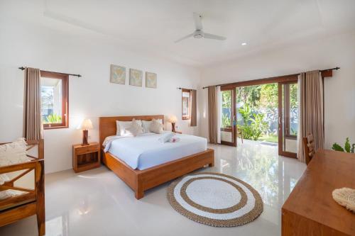 a white bedroom with a bed and a table at Nusa Indah Onai Hotel in Nusa Lembongan