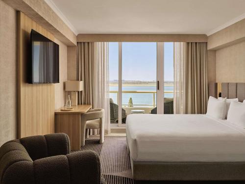 a hotel room with a bed and a view of the ocean at The Brighton Hotel Sydney - Mgallery Collection in Sydney