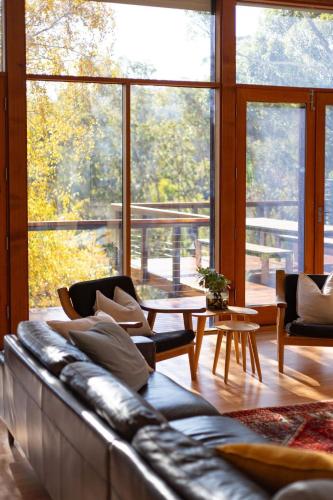 a living room with a couch and a large window at Whistlewood - Stunning Views in the Adelaide Hills in Upper Sturt
