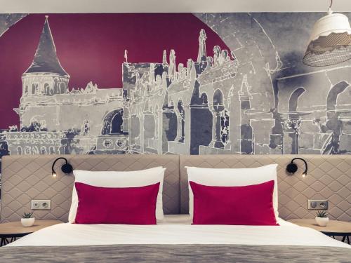 a bed with two red pillows in front of a castle mural at Mercure Budapest Castle Hill in Budapest