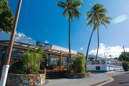 un barco estacionado frente a un edificio con palmeras en Nomads Airlie Beach, en Airlie Beach