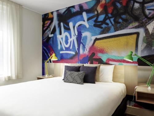 una camera con un letto bianco e un dipinto di ibis Melbourne Hotel and Apartments a Melbourne